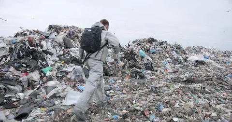 A man in special clothes with a black backpack runs along the dump. Stock Footage 127650643