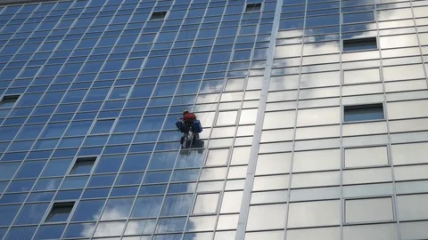 A man with special equipment is cleaning windows in a business center. Video stock 129763813