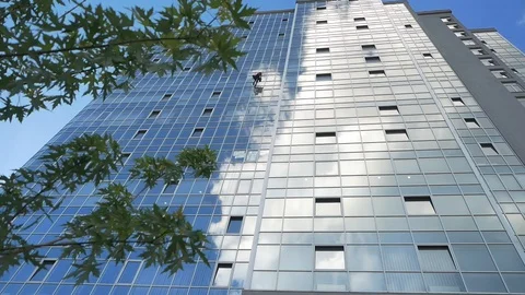 A man with special equipment is cleaning windows in a business center. Video stock 129764077