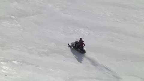 Man speeding a snowmobile on top of a mountain with a  girl behind him as a Stock Footage 145540444