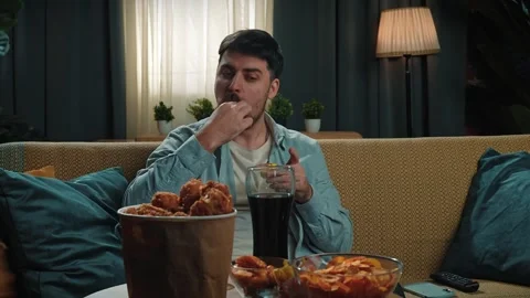 Man spending time at home with fast food delivery, sits on couch watching tv Stock Footage 305490756