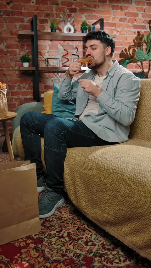 Man spending time at home with fast food delivery, sits on couch watching tv Stock Footage 305495991