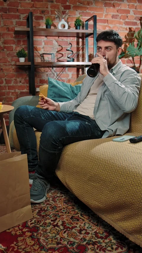Man spending time at home with fast food delivery, sits on couch watching tv Stock Footage 305496834