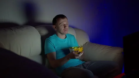 Man spends a boring evening watching TV sitting on a sofa and eating chips Stock Footage 130904984