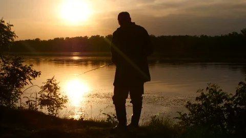Man spends his leisure in nature and fishes at sunset Stock Footage