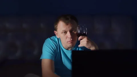 Man spends the night sitting in front of the TV with a glass of wine Stock Footage 136033265
