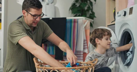 Man spends time with young child in laundry room, bathroom, performs household 動画素材 200843176