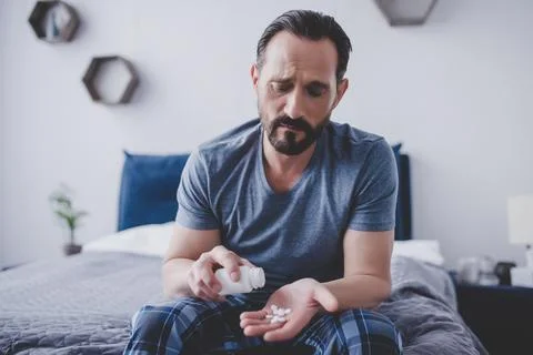 Man spilling pills from container on the hand Stock Photos