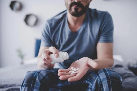 Man spilling pills from container on the hand Stock Photos