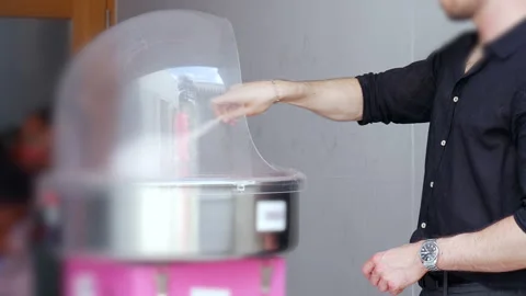 Man spinning cotton candy inside clear dome machine at event or party, vendor pr Stock Footage 313074657