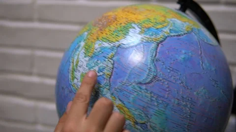 Man spinning a globe and pointing on it. Learning about the globe Stockbeeldmateriaal 120305385
