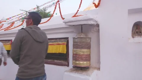 Man spinning prayer wheels outside a Tibetan Buddhist temple in Kathmandu Stock Footage 77446759