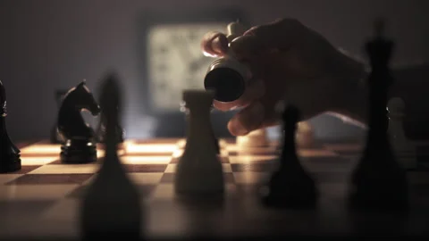 A man is spinning a queen piece in his hand over a chessboard Stock Footage 312819757