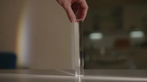 Man spinning triangular glass prism, light passes through creating beautiful Stock Footage 312330142