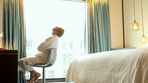 Man spins sitting on a rotating stool in his hotel room after taking a shower 스톡 동영상 98782188