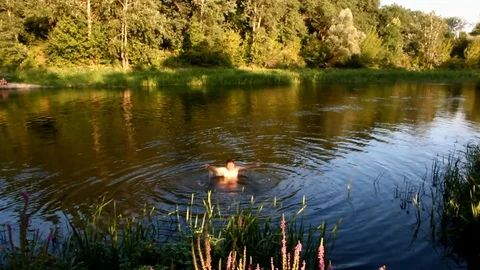 A man splashes in the river in the soft rays of the evening sun Stock Footage 100980112