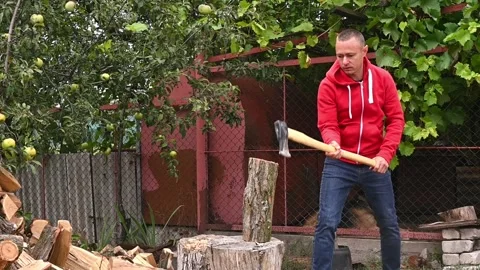Man splits a log with an axe, the log breaking in half after Video stock 335393533