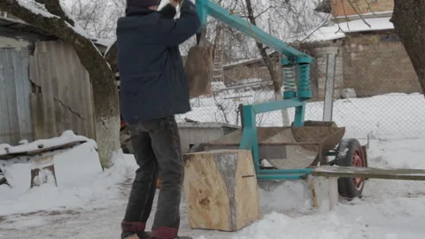 Man splitting wood with mechanical spring lever log splitter in winter Stock Footage 345652398