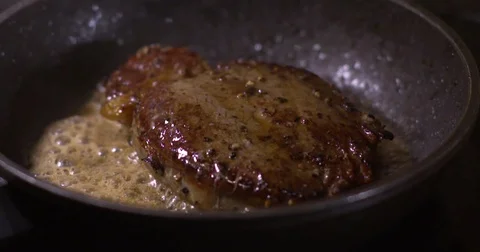 Man spoons foaming butter over steak cooking on hot pan. Slow motion Stock Footage