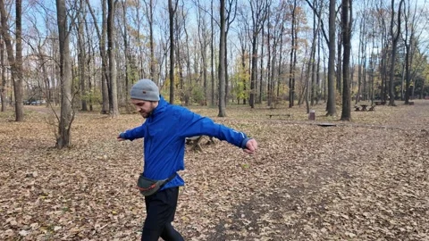 Man in sportswear doing warm-up exercises after jogging in autumn forest Stock Footage 316840234
