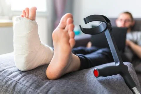 Man with a sprained ankle sitting on a sofa at home Stock Photos