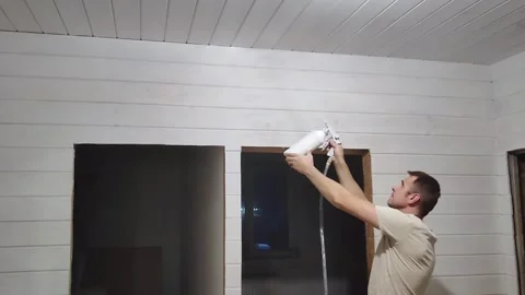 A man spray paints a ceiling with white paint Stock Footage 267102096