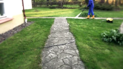 Man spray wash path with high pressure sprayer in garden. 4K Stock Footage 126527483