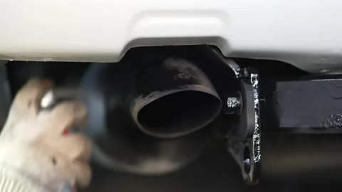 Man spraying black protective aerosol coating onto car exhaust tailpipe. Stock Footage 344365978