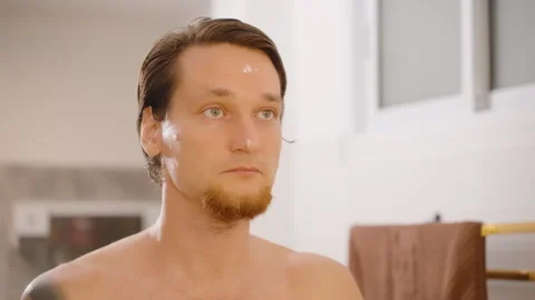 Man Spraying Face Mist During Skincare Routine in Bathroom, front angle, Video stock 317219616