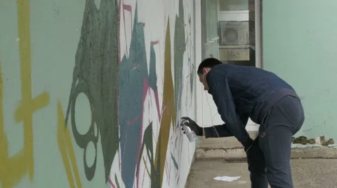 Man spraying graffiti on the wall, wall decoration, design, artwork, artistic. Stock Footage 57127546
