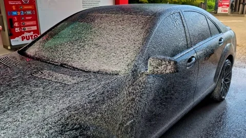 Man spraying thick white cleaning foam on luxury dark sedan at outdoor Video stock 332249672