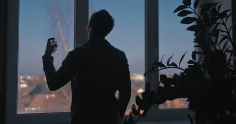 A man sprays perfume while standing by a window in a classic suit Vidéo 330308642