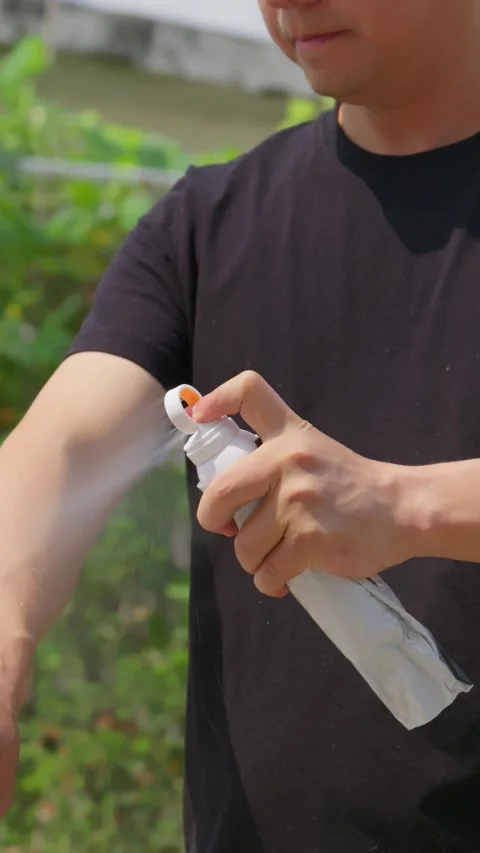 A man sprays sunscreen on both arms to protect skin from sunburn in summer. Stock Footage 336038219