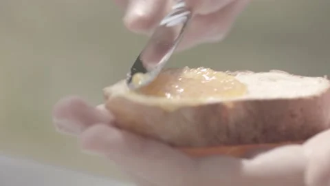 A man spreading jam on bread outside, close up from the little jar Stock Footage 135397049