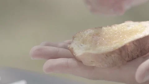 A man spreading jam with a knife on bread, outside, close up Stock Footage 135397020
