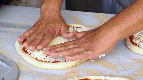 Man spreading a layer of cheese on a homemade pizza. Hands at work. Video stock 311069031