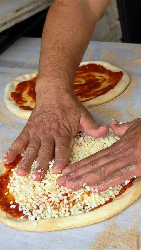Man spreading a layer of cheese on a homemade pizza. Hands at work. Stock Footage 311115316