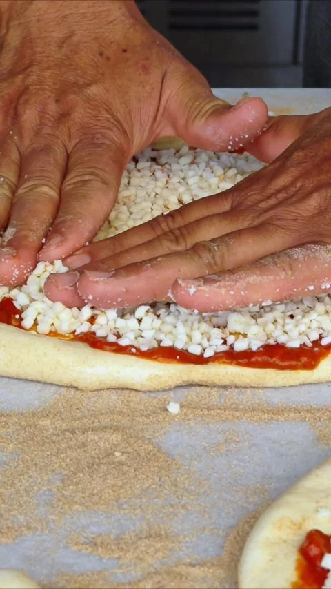 Man spreading a layer of cheese on a homemade pizza. Hands at work. Stock Footage 311753532