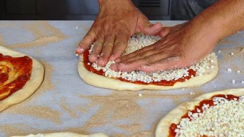 Man spreading a layer of cheese on a homemade pizza. Hands at work. Stock Footage 311998060