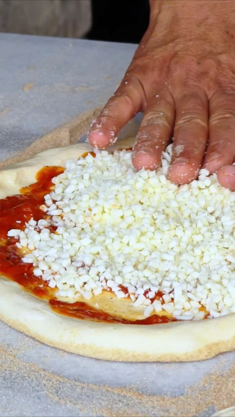 Man spreading a layer of cheese on a homemade pizza. Hands at work. Stock Footage 312612150