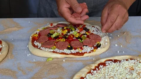 Man spreading a layer of cheese, meat, vegetables on a homemade pizza. Stock Footage 311064407
