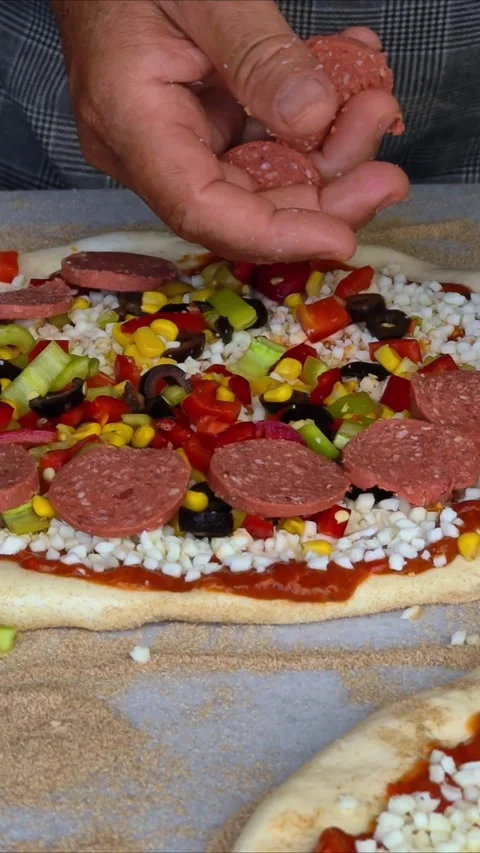 Man spreading a layer of cheese, meat, vegetables on a homemade pizza. Stock Footage 312637141