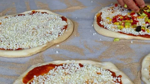 Man spreading a layer of cheese, vegetables on a homemade pizza. Hands at work. Video stock 311019289