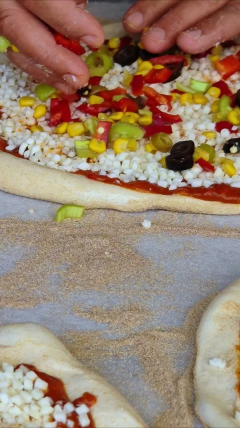 Man spreading a layer of cheese, vegetables on a homemade pizza. Hands at work. Stock Footage 311429183