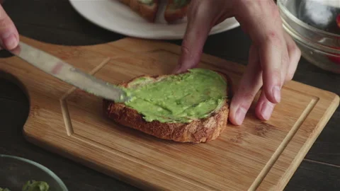 Man spreading mashed avocado on toast Stock Footage 152274737