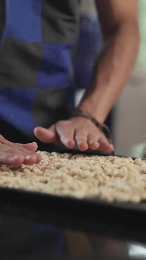 Man spreading peeled peanuts on a tray in the kitchen Stock Footage 305855177
