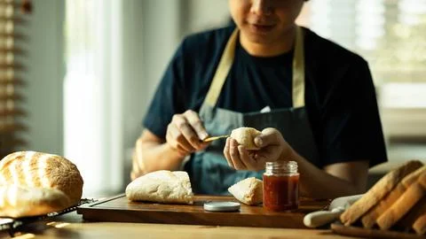 Man spreading sweet raspberry jam on bread during for breakfast or brunch in Stock Photos