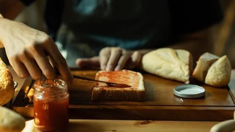 Man spreading sweet raspberry jam on bread during for breakfast or brunch in Stock Photos