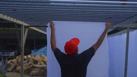 Man Spreading white sheet of fabric cloth outside, penang Stock Footage 108798000