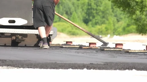 Man spreads asphalt using a long tool Vídeo Stock 343699311